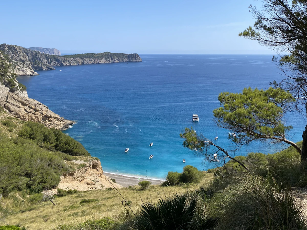 Turkis bukt med båter under klippene ved Alcúdia